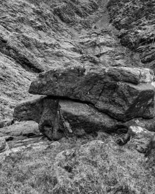 Görüntü dağlık bir bölgede geniş ve engebeli bir kaya oluşumunu gösteriyor. Nadir bitki örtüsü ve engebeli arazi..