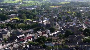 Video bir kasabayı tasvir ediyor. Evler esasen gri çatılı, yüksek bir kilise kulesi sahneye hakim..