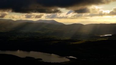 Gün batımının çarpıcı görüntüsüne tanık olun. Uzak dağlara ve dingin bir göle ışık saçıyor. Doğal güzelliklerle dolu sakin bir atmosfer yaratıyor..