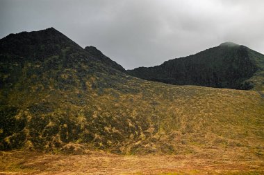 Engebeli dağlar ve yemyeşil vadilerle çevrili Carrauntoohil geçidi İrlanda 'nın doğal manzarasının güzelliğini yakalıyor. Kara bulutlar değişen hava hakkında ipucu verir.