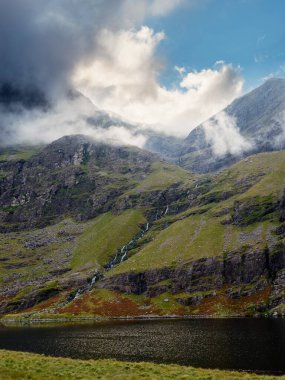 Lough Gouragh 'ın görkemli manzarası İrlanda' da yükselen dağlar ve sürüklenen bulutlarla çevrilidir..