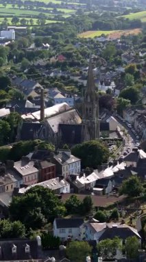 Videoyu ağaçlar ve büyük bir kilise kulesiyle noktalayan gri çatılı konutlar dolduruyor..