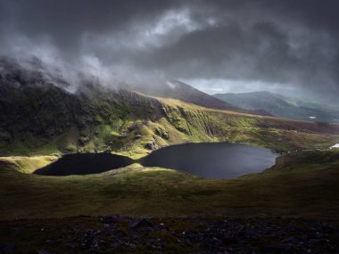 County Kerry 'den Coomloughra Lough, karanlık ve yükselen bulutların altında büyüleyici, gür manzaralar sergiliyor. Sakin göller etrafındaki dağları yansıtıyor, nefes kesici bir manzara yaratıyor..