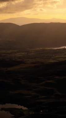 Gün batımında dağ sırası. Alçak asılı bulutlar koyu ve yoğundur. Güneş ışınları bulutları delip, yamaçlara ışık saçıyor. Manzara görüntüsü tamamlandı..