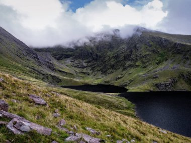 Coomloughra Lough, Kerry County 'deki nefes kesen dağların arasına kuruludur. Üzerinden bulutlar akmaktadır. Verimli yeşil arazi, karanlık suların çarpıcı bir karşıtlığıdır..