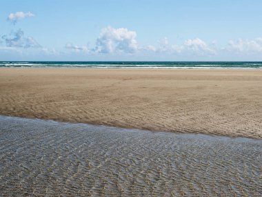 Dalgalar, açık mavi bir gökyüzünün altında yumuşak kumların uzandığı Inchydoney Sahili 'nde nazikçe kıyıya çarpar. Güneş ışığı, sahil güzelliğinin tadını çıkaran ziyaretçiler için sakin atmosferi güçlendirir..