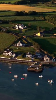 Kırsal İrlanda manzarası sakin sularda kayıklar ve akşam ışığında yemyeşil alanlar..