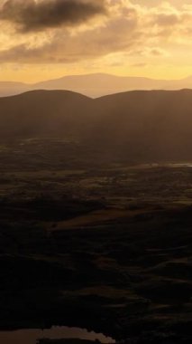 Videoda gölü olan geniş bir vadi gösteriliyor. Arka planda dağlar dik durur. Günbatımının turuncu ışığı sahnenin derinliğini arttırır.