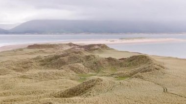 Sakin sularla çevrili kıyı şeridi boyunca uzanan sersemletici kumullar ve arka planda yumuşak tepeler. Huzurlu ortam sabahları tefekküre ve keşfe davet ediyor..