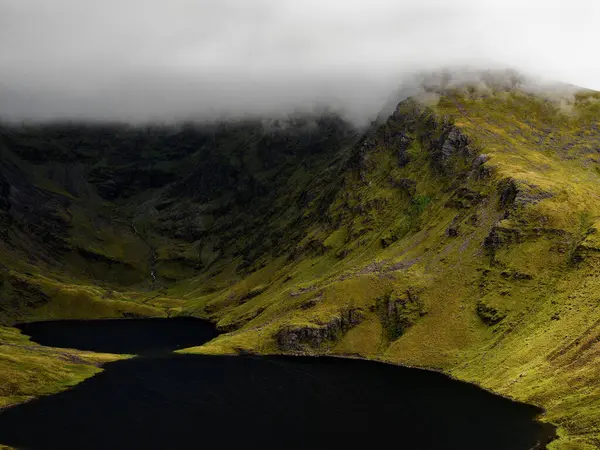 Coomloughra Lough, engebeli tepeler ve sisle çevrili sakin güzelliğini sergiliyor. Karanlık sular, doğa aşıkları için mükemmel bir ortam yaratır..