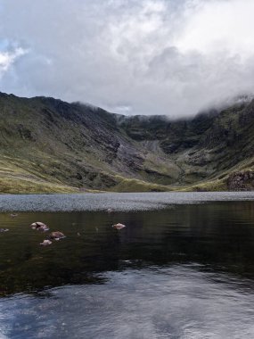 Coomloughra Lough bir vadiye yerleşmiş, bulutlu bir günde büyüleyici İrlanda manzarasını sergiliyor..