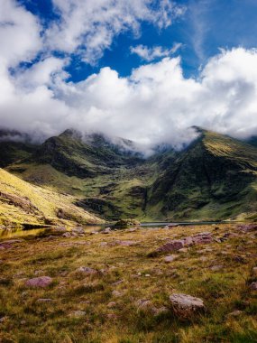 Lough Callee 'nin etrafı çarpıcı İrlanda dağlarıyla, yemyeşil ve bulutlarla dolu dinamik bir gökyüzüyle çevrilidir. Huzurlu su etrafındaki manzarayı güzel bir şekilde yakalar..
