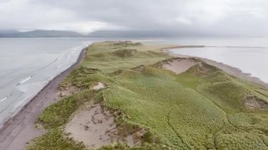 İrlanda 'nın yemyeşil ve dingin sularıyla bulutlu havalarda güzel kıyı manzarası.