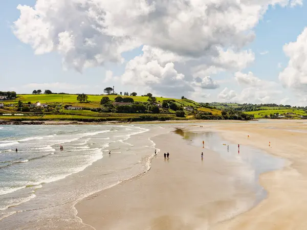 West Cork, 25 Haziran 2023. İnsanların yaz gününün tadını çıkardığı çarpıcı bir plaj manzarası. Kum, deniz ve yeşil tepeler arasındaki zıtlık huzurlu ve güzel bir manzara yaratır..