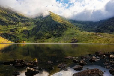 Lough Callee sakin suları ve dramatik dağları olan güzel bir yerdir. Manzara, bulutlu bir gökyüzünün altında İrlanda 'nın manzaralı sükunetinin özünü yakalıyor..