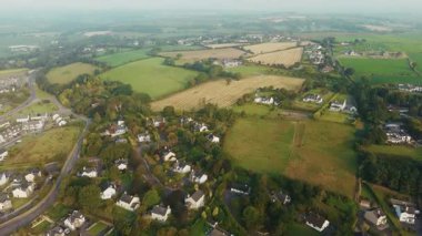 Clonakilty, İrlanda 'nın güzel bir sabahında sakin bir hava manzarasına tanık olun. Yeşil tarlaların arasına yuva yapmış evleri gör ve güzel İrlanda manzarası boyunca dolambaçlı yolları takip et..