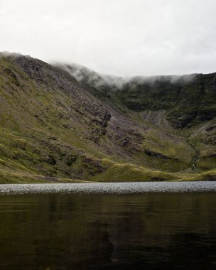 Heybetli uçurumlar ve puslu tepelerle çevrelenmiş sakin dağ gölü, zıtlıkların nefes kesen manzarası..