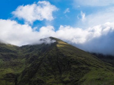 İrlanda 'nın Kerry ilçesinde kısmen bulutlarla kaplanmış engebeli Carrauntoohill Dağı manzarası.