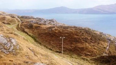 İrlanda 'da güneşli bir günde kıyı şeridi manzarası. Yol Atlantik Okyanusu 'nun yakınındaki bir yamaç boyunca esiyor..