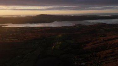 Gün batımında kırsal kesimde geniş bir bakış açısı sergileniyor. Dağlar ve göl, altın saat boyunca İrlanda kıyılarıyla çarpıcı bir ışık altında buluşur..