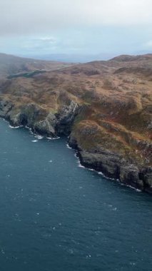 İrlanda 'da dalgaların kayalara çarptığı kayalık bir sahil. Gri ve kasvetli bir gün.