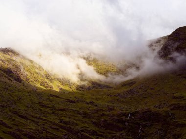 Sisli bulutlar Carrauntoohill vadisinde sürükleniyor. Alçak asılı bulutlar dağların zirvesini gizler ve İrlanda manzarasının dramatik atmosferini artırır..