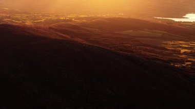 İrlanda 'da gün batımında kırsal ve göl manzaralarının manzarası sakin ve huzurlu ortamları gösteriyor..