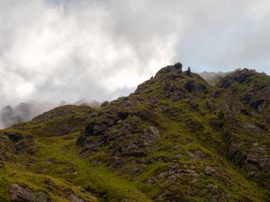 Bulutlu bir günde İrlanda 'nın Carrauntoohill geçidinde yeşil manzarayı ve engebeli uçurumları görmek.