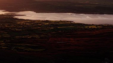 Ireland 'ların büyüleyici manzarasında çarpıcı bir günbatımına tanık olun. Bereketli yeşil tepeler sıcak, altın ışıkla yıkandı. Büyüleyici bir sahne.