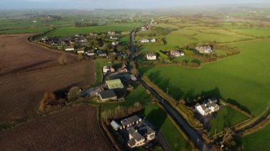 İrlanda 'nın kırsal kesiminde hava perspektifi. Özellikleri çiftlik evleri, parlak yeşil tarlalar ve akşam erken saatlerde arazide dolanan dar bir yol..