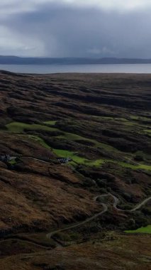 Bulutlu bir günde denize bakan uzak İrlanda manzarasını, yeşil tarlaları ve kırsal manzarayı keşfediyorum..