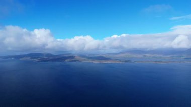 İrlanda 'da Kerry ilçesinin kıyı şeridini ve dağlarını gösteren deniz manzarası. Dingle Yarımadası güzel bir günde bulutlar tarafından kısmen gizleniyor..