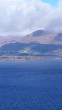İrlanda kıyı şeridinin gündüz manzarası. İrlanda 'nın Kerry ilçesindeki okyanusu, dağları ve bulutlu gökyüzünü gösteriyor..