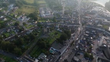 Clonakilty, İrlanda, 7 Eylül 2024. Clonakilty, İrlanda 'nın güneşli bir günde gökyüzünden izlenen bir videosu. Ana caddeden geçen arabalar, kasabanın binaları ve çevresindeki kırsal bölgeler..