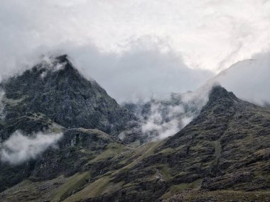 Görüntü bir dağ yamacına odaklanıyor. Bileşimi ağırlıklı olarak küçük şelaleleri olan kaya ve tek tük bitki yaşamından oluşur. Bulutlar en üst kısımda.