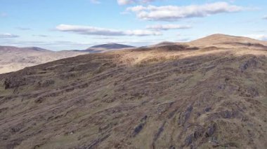 Soluk bir gökyüzünün altındaki ıssız, kayalık dağların geniş bir hava manzarası. Belgeseller ve macera filmleri için mükemmel..