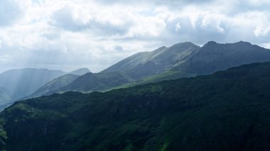 Bulutlu bir gökyüzünün altındaki sakin dağ manzarası. Seyahat, doğa ya da macera temaları için mükemmel.