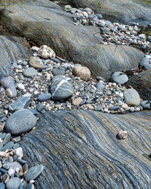 Sahne, sahil şeridinde büyük, pürüzsüz kayalar ve daha küçük çakıl taşlarını gösteriyor. Açığa çıkan kayalar, Batı Cork 'ta okyanus kenarında ilginç dokular sergiliyor..