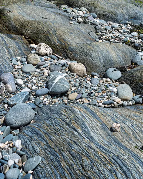 Sahne, sahil şeridinde büyük, pürüzsüz kayalar ve daha küçük çakıl taşlarını gösteriyor. Açığa çıkan kayalar, Batı Cork 'ta okyanus kenarında ilginç dokular sergiliyor..