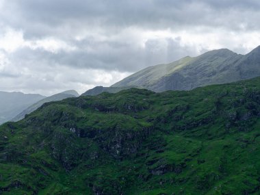 Yuvarlanan yeşil tepeler dramatik bir dağ silsilesiyle karşılaşıyor. Nefes kesen manzara arka plan için mükemmel..
