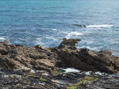 Kıyıda, berrak okyanus suyuyla küçük bir koy oluşturan serin kaya oluşumları var. Batı Cork, İrlanda 'da kıyı şeridi boyunca kayalara vuran dalgalar var..