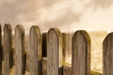 Beton duvarda gölgesi olan ahşap bir çit.