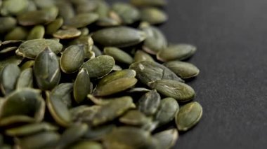 Siyah bir arkaplanda kurumuş kabak tohumları.