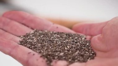Elleri avuçlarında ve yavaş çekimde düşen chia tohumları. Doğal antioksidan ve omega yağ asitlerinin kaynağı