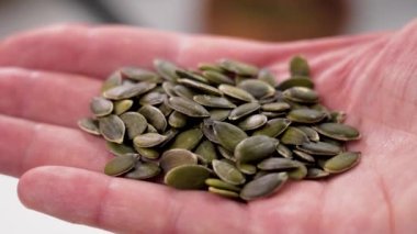 Elinde kabak çekirdeği var. Mutfakta taze soyulmuş yeşil malzeme var.