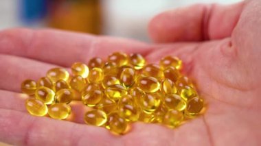 Omega 3 saydam altın kapsüller. Bir avuç dolusu besin takviyesi var. Yakın plan. Çoklu doymuş yağ asitleri