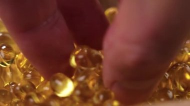 Bir el Omega 3 saydam altın kapsülleri alır. Polyunurated yağ asidi hapları.
