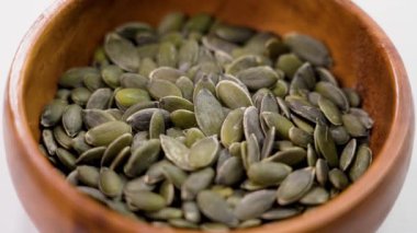 Odunsu kırsal bir kasede kabak çekirdeği. Çiğ taze soyulmuş yeşil malzeme. Döndürme