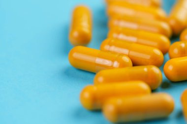 Mavi zemin üzerinde curkimin tozu bulunan sarı şifalı kapsüller. Alternatif bitkisel tıp konsepti. Döndürme