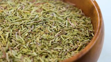 Kurutulmuş Rosemary baharatı. Ahşap kabın içindeki kuru bitki kokulu yapraklar. Makro. Döndürme